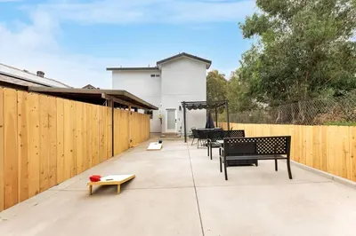 a patio with black benches and a wooden fence at Urban Retreat Fun Relax Self Check-In Hot Tub Foosball Fire Pit Cornhole in The Woods Trailer Park