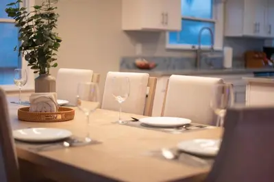 a wooden table with wine glasses and plates on it at NEW! Pt Loma Paradise: Remodel - Pool – Game Room – WOW! in San Diego