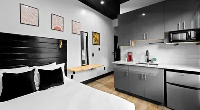 a bedroom with a white bed and a kitchen at Balboa Park Hotel Downtown Little Italy in San Diego