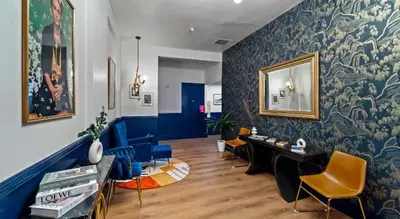 a living room with blue walls and yellow chairs at Balboa Park Hotel Downtown Little Italy in San Diego