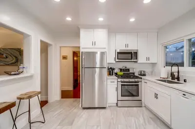 a kitchen with white cabinets and a stainless steel refrigerator at Spectacular Seaview Oasis -Views Spa Game Room in San Diego