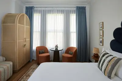 a bedroom with a bed and chairs and a window at Granger Hotel San Diego Downtown Gaslamp Quarter, a Member of Design Hotels in San Diego