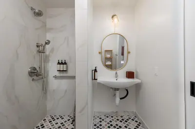 a bathroom with a shower and a sink and a mirror at Granger Hotel San Diego Downtown Gaslamp Quarter, a Member of Design Hotels in San Diego
