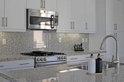 a kitchen with white cabinets and a stainless steel microwave at Fun In The Sun 2 Bed 2 Bath Home in Oceanside