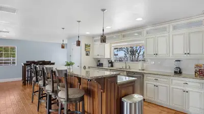 a kitchen with white cabinets and a bar with stools at Wine Country Retreat Gorgeous Views Minutes to Wineries in Temecula