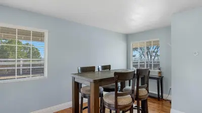 a dining room with a table and chairs and two windows at Wine Country Retreat Gorgeous Views Minutes to Wineries in Temecula
