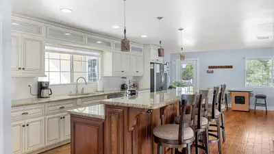 a kitchen with white cabinets and a island with bar stools at Wine Country Retreat Gorgeous Views Minutes to Wineries in Temecula