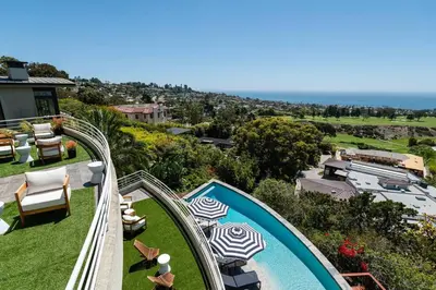 a swimming pool with chairs and umbrellas on top of a house at La Jolla Ocean View Mansion 2 in San Diego