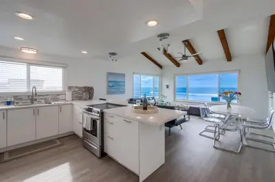 a kitchen with white cabinets and a table and chairs at Mermaid's Penthouse in San Diego