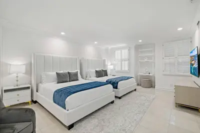 a white bedroom with two beds and a television at La Jolla Top Of The World Mansion in San Diego