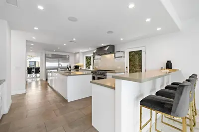 a kitchen with white walls and a counter with bar stools at La Jolla Top Of The World Mansion in San Diego