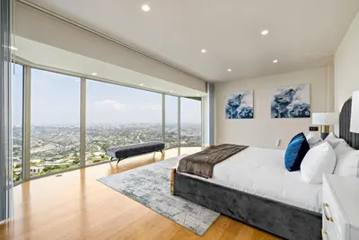 a bedroom with a large bed and large windows at La Jolla Top Of The World Mansion in San Diego
