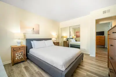 a bedroom with a large white bed and a room with a bed sqor at Charming Home Just Steps from the Beach 2 Bedroom, Private Back Patio, & Free WiFi in Newport Beach
