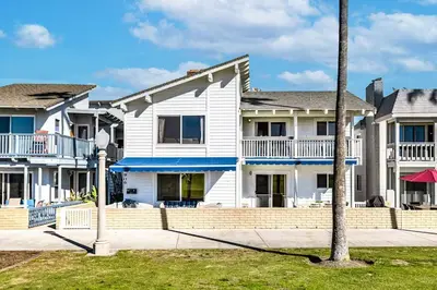 a row of white houses with a palm tree at Stunning 2nd Floor Beachfront Home with Balcony, Ocean Views, and Prime Location in Newport Beach