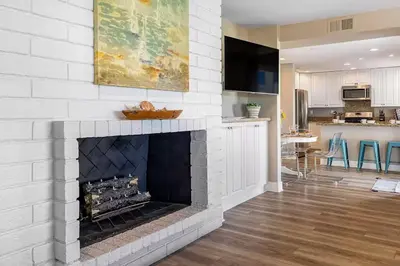 a living room with a white brick fireplace at Oceanfront Oasis in Newport Beach Steps to Balboa Park, Pier, and The Fun Zone! in Newport Beach