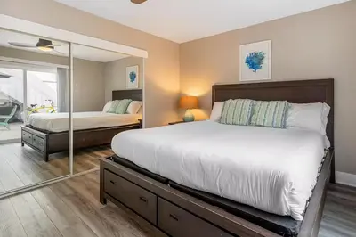 a bedroom with a large bed and a mirror at Oceanfront Oasis in Newport Beach Steps to Balboa Park, Pier, and The Fun Zone! in Newport Beach