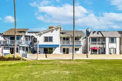 a large white house with a lawn in front of it at Oceanfront Oasis in Newport Beach Steps to Balboa Park, Pier, and The Fun Zone! in Newport Beach