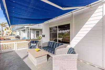 a patio with wicker chairs and a table on a porch at Beachside Oasis in Newport Beach Steps to Balboa Park, Pier, and The Fun Zone! in Newport Beach