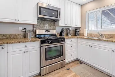 a kitchen with white cabinets and a stove top oven at Beachside Oasis in Newport Beach Steps to Balboa Park, Pier, and The Fun Zone! in Newport Beach