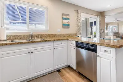 a kitchen with white cabinets and a dishwasher at Beachside Oasis in Newport Beach Steps to Balboa Park, Pier, and The Fun Zone! in Newport Beach