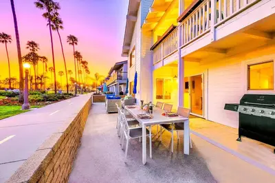 a table and chairs on a patio with palm trees at Beachside Oasis in Newport Beach Steps to Balboa Park, Pier, and The Fun Zone! in Newport Beach