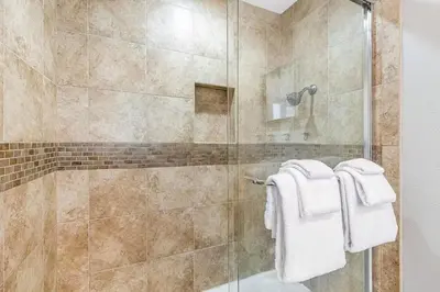 a bathroom with a glass shower with towels at Beachside Oasis in Newport Beach Steps to Balboa Park, Pier, and The Fun Zone! in Newport Beach