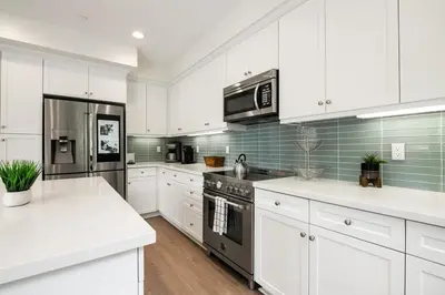 a kitchen with white cabinets and a black refrigerator at Makena By The Sea, 3 bed home near beach in Oceanside