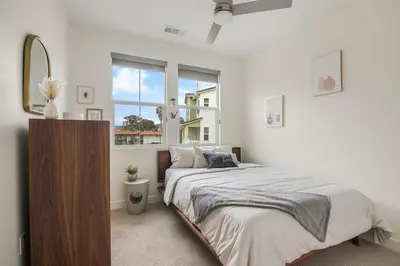 a bedroom with a bed and a mirror and a window at Makena By The Sea, 3 bed home near beach in Oceanside