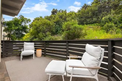 a patio with two white chairs and a fence at Makena By The Sea, 3 bed home near beach in Oceanside