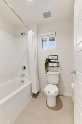 a white bathroom with a toilet and a bath tub at Sunnyside Up San Diego Gem in San Diego