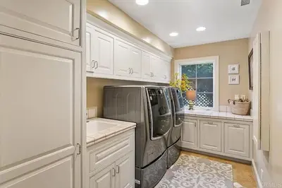 a kitchen with white cabinets and a black refrigerator at Enchanting French Inspired Chateau with Beach Club! in South Oceanside