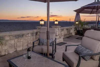 a patio with chairs and an umbrella and a table at Oceanfront 3BR Home with Pool Table & Patio in Newport Beach