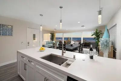 a kitchen with a sink and a living room at 8BR Beach Duplex with Ocean Views, Patio & Pool Table in Newport Beach