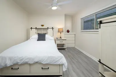 a white bedroom with a large bed and a window at 8BR Beach Duplex with Ocean Views, Patio & Pool Table in Newport Beach