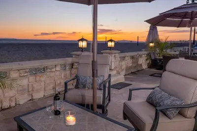 a patio with chairs and an umbrella and a table at 8BR Beach Duplex with Ocean Views, Patio & Pool Table in Newport Beach