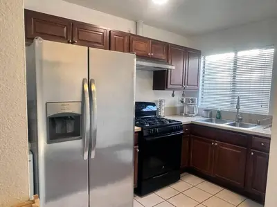 a kitchen with wooden cabinets and a stainless steel refrigerator at Fabulous Guesthouse in Mount Helix La Mesa in Grossmont