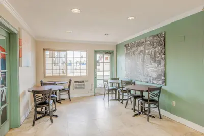 a dining room with tables and chairs and green walls at Hotel Avenida - Oceanside Camp Pendleton in Oceanside