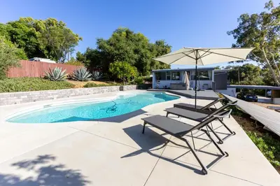 a pool with two lounge chairs and an umbrella at Mid-Century Masterpiece Tree house, Pool & Spa in Escondido