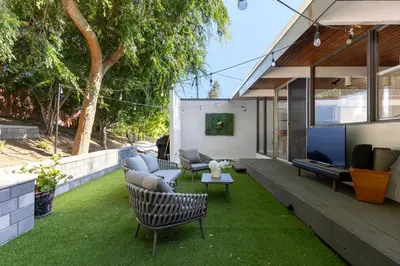 a patio with chairs and a tv on the grass at Mid-Century Masterpiece Tree house, Pool & Spa in Escondido