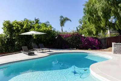 a swimming pool with two chairs and an umbrella at Mid-Century Masterpiece Tree house, Pool & Spa in Escondido