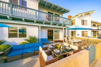 a patio with a blue couch and tables and umbrellas at Newport Beach Condo with Patio Perfect Location on the Boardwalk in Newport Beach