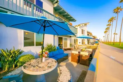 a patio with a table with a blue umbrella at Newport Beach Condo with Patio Perfect Location on the Boardwalk in Newport Beach