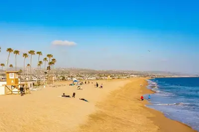 people on a beach with palm trees and the ocean at Newport Beach Condo with Patio Perfect Location on the Boardwalk in Newport Beach