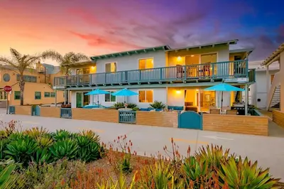 a house with a balcony with blue umbrellas at Newport Beach Condo with Patio Perfect Location on the Boardwalk in Newport Beach