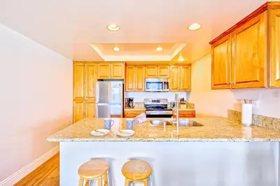 a kitchen with wooden cabinets and a counter with stools at Condo in Newport Beach with Private Balcony and Ideal Location by the Pier in Newport Beach