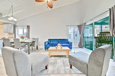 a living room with a blue couch and a table at Balboa Peninsula Hidden Gem with Private Balcony & Stunning Views in Newport Beach