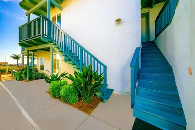 a building with blue stairs and plants in front of it at Balboa Peninsula Hidden Gem with Private Balcony & Stunning Views in Newport Beach