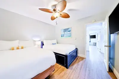 two beds in a room with a ceiling fan at Oceanfront Condo in Newport Beach with Private Balcony and Perfect Location by the Pier in Newport Beach