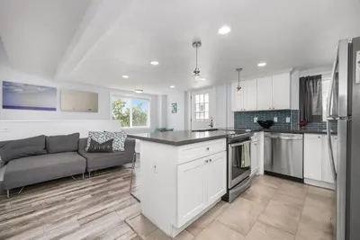 a kitchen with white cabinets and a couch in a room at Perfect Surf Casa in Newport Near Beach and Pier in Newport Beach