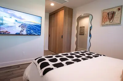 a bedroom with a bed and a tv on the wall at Modern 1 BR Cottage Steps 2Beach in San Diego